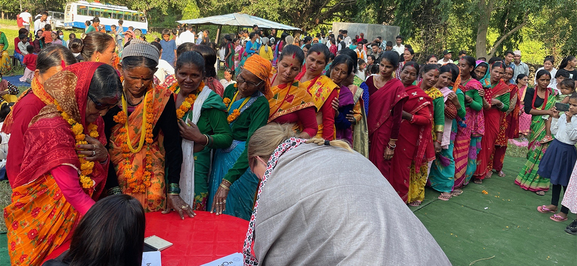 a group of women in colorful dresses standing around a table